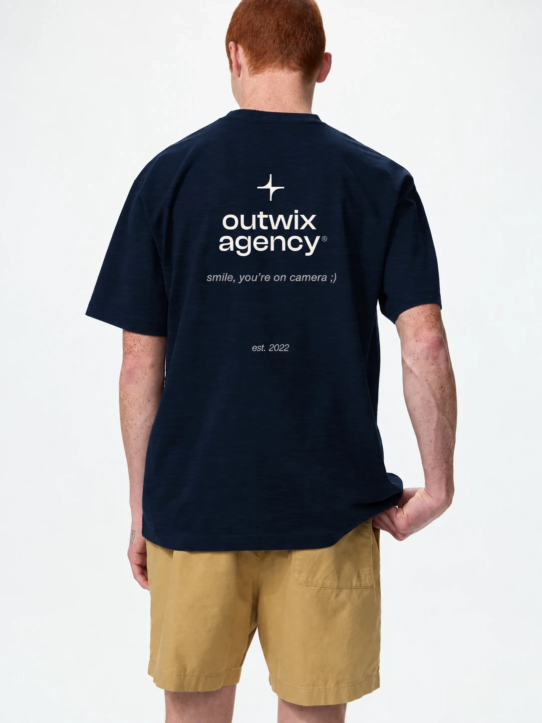 Navy T-shirt van Outwix Agency met het logo en 'smile, you're on camera ;)' op de rug